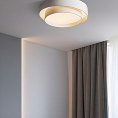 a white ceiling light in a room with curtains