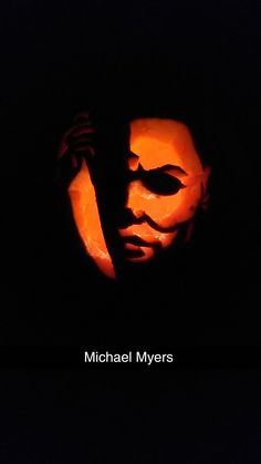 michael myers's face carved into the side of a pumpkin with his hands on his head