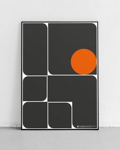 a black and white poster with an orange dot on it's center, against a white wall