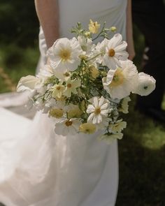 a bride holding a bouquet of white and yellow flowers