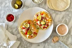 two pita breads on a plate with dipping sauce and other ingredients around them