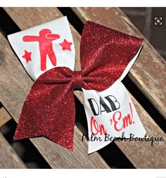 a red and white bow sitting on top of a wooden bench with the words dad on it