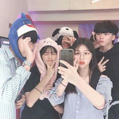 four people taking a selfie in front of a mirror with stuffed animals on their heads