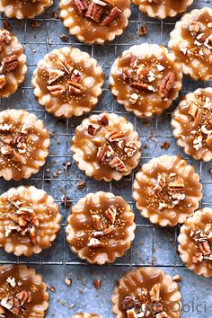 several pecan pies on a cooling rack covered in caramel and pecans