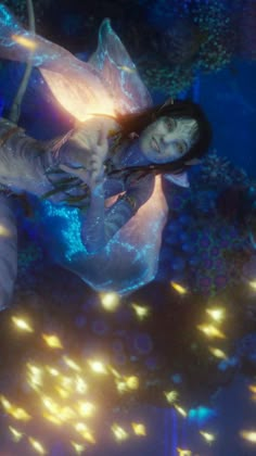 a woman is floating in the water with lights around her and holding on to something