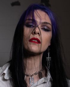 a woman with purple hair and piercings on her face, wearing silver necklaces