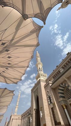 an outdoor area with many umbrellas and buildings in the background under a cloudy blue sky