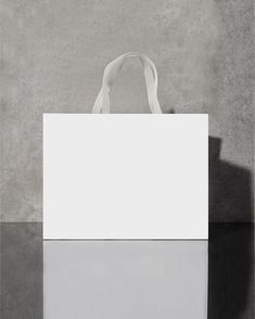 a white bag sitting on top of a table next to a black and white wall