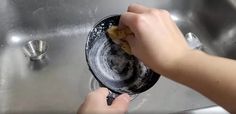 a person is washing dishes in a stainless steel sink with a rag on the bottom