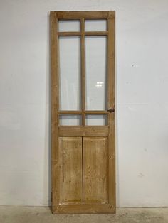 an old wooden door with glass panels on the front and side, against a white wall