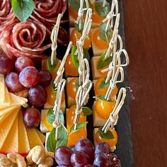 an assortment of cheeses, fruits and nuts arranged on a platter with flowers