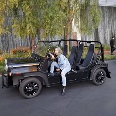 a woman sitting on the back of a black golf cart