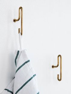 two towels hanging from hooks on a wall next to a towel rack and coat hook