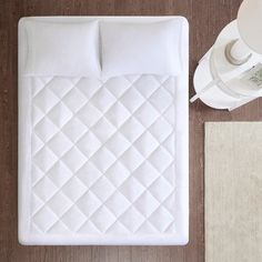 a white bed sitting on top of a wooden floor next to a cup and saucer