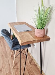 a desk with a laptop on it and a plant in a vase next to it