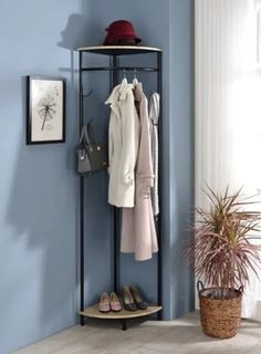 a coat rack with shoes and purses hanging on the wall next to a potted plant