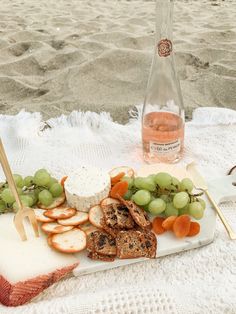 a plate with grapes, meat and cheese on it next to a bottle of wine