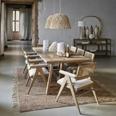 a dining room table with chairs and vases on the floor in front of it