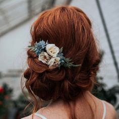 a woman with red hair and flowers in her hair is seen from the back view