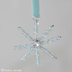 a glass snowflake ornament hanging from a string