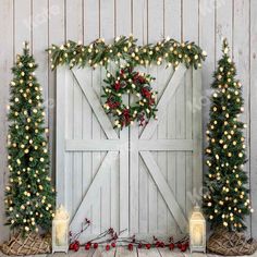 a barn door decorated for christmas with lights and greenery on the side, surrounded by candles