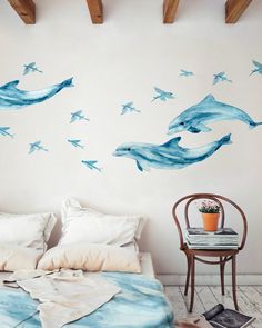 a bed room with a neatly made bed and two dolphins on the wall