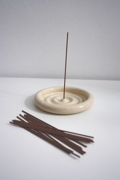 incense sticks in a bowl with a stick sticking out of the top on a white surface