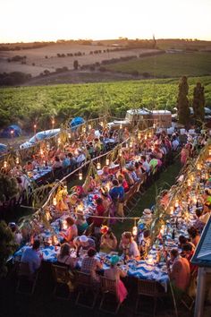 a large group of people sitting at tables in the middle of a field