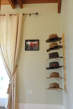 hats are hanging on the wall next to a window