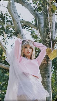 a woman in a white dress is sitting on a tree branch with her hands behind her head