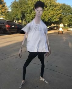 a young man in white shirt and black pants playing with a frisbee on street