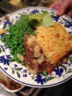 a blue and white plate topped with food next to broccoli on a table