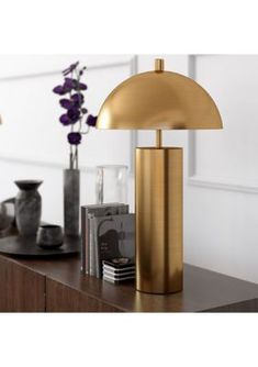 An ultra-modern take on a Mid-Century design, this table lamp offers timeless sophistication. The metal dome shade sits atop a sleek column base, creating a harmonious play of classic shapes. Simple yet eye-catching, its streamlined look and warm golden brass finish will illuminate your bedside, reading nook, or living room in style. Handcrafted brass finish is applied to the steel base. Paired with a dome-shaped shade. This shade is made of metal. Rated for one 60W incandescent bulb; 9W LED bulb, 13W fluorescent (CFL) bulb, or 9W self-ballasted LED bulb. E26-base bulb. Includes a 6 ft. cord. | Hinkley & Carter York Table Lamp Sideboard Decor, Column Base, Side Lamps, Metal Table Lamp, Gold Lamp, Fixture Table, Gold Table Lamp, Table Metal, Art Deco Lamps