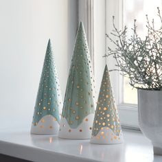 three ceramic trees sitting on top of a white shelf