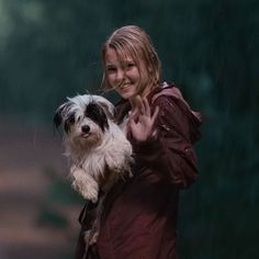 a woman holding a dog in her arms and giving the peace sign with both hands