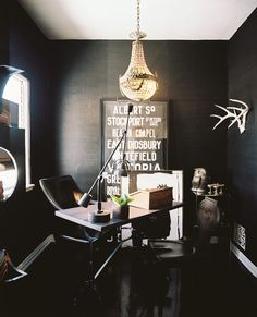 a black and white room with a chandelier hanging from the ceiling over a desk