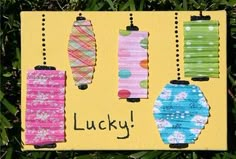 a sign that says lucky on it in front of some grass with paper lanterns hanging from them