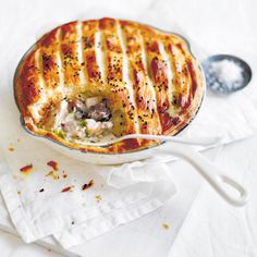 a casserole dish with meat and vegetables in it on a white tablecloth