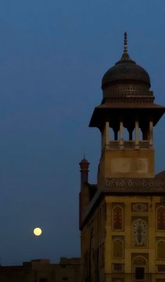 the moon is setting over an old building