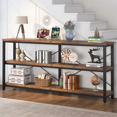 a book shelf with books and vases on it in front of a stair case