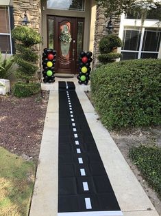 a black and white striped road leading to a house with traffic lights on each side