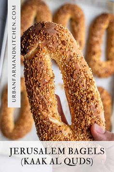 a person holding up a bagel with sesame seeds on it and the words, jesusalem bagels kaka al ouds