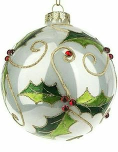 a glass ornament with holly leaves and red berries