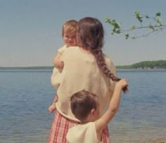 two children standing on the shore of a body of water