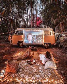 a person laying on the ground in front of a van with a screen showing a movie