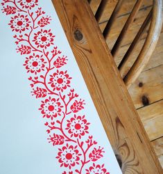 a red and white floral design is on the side of a wooden chair