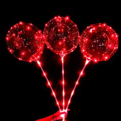 three red lighted lollipops in the dark with string lights on it's sides