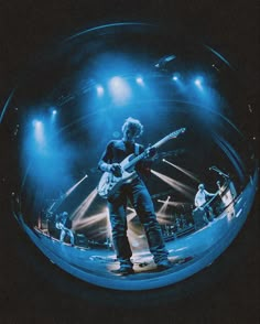 a man standing on top of a stage holding a guitar