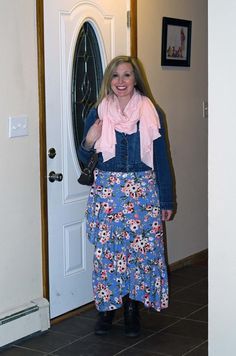 a woman standing in front of a door wearing a blue dress and pink scarf over her neck