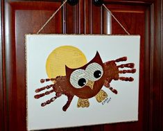 an owl made out of handprints hanging on a door